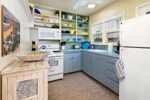 a kitchen with blue cabinets and a white refrigerator at Charming Beach Bungalow in Seal Beach