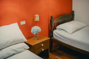 a bedroom with two beds and a vase of flowers on a table at Hostal Vacaciones Nicas in León