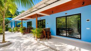 a blue house with a patio with palm trees at Garden Hostel Koh Rong in Koh Rong Island