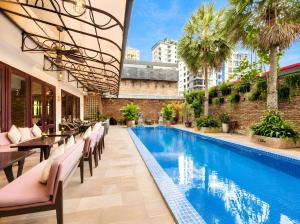 a swimming pool with tables and chairs next to a building at Norodom Clover Hotel in Phnom Penh