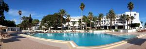 a swimming pool in front of a building with palm trees at Hotel Bel Azur Thalasso & Bungalows in Hammamet