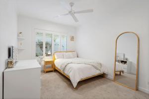 a white bedroom with a bed and a mirror at Tallows Coastal Retreat in Kingscliff +19 photos