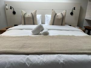 ein großes Bett mit weißen Laken und Kissen in der Unterkunft Koi liv-Inn Bedfordview ll Modern Guest House Near OR Tambo in Bedfordview