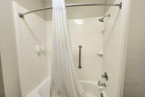 a white shower curtain in a bathroom with a tub at Days Inn & Suites by Wyndham Katy in Katy