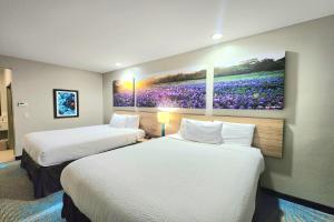 a hotel room with two beds and a painting on the wall at Days Inn & Suites by Wyndham Katy in Katy