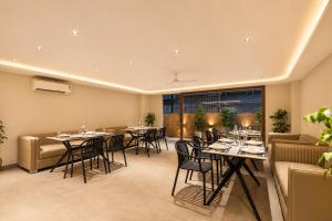 a restaurant with tables and chairs and a large window at Alaya Stays Luxora Suites, Golf Course Rd near galleria in Gurgaon