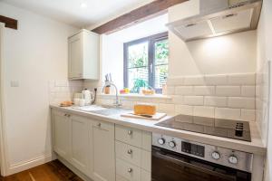 a kitchen with white cabinets and a sink and a window at 2 Bed in Carmel oc-wai210 in Llanerchymedd