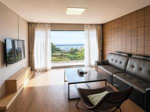a living room with a couch and a large window at Y Resort Jeju in Seogwipo