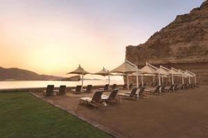 a row of chairs and umbrellas on a beach at Al Husn Hotel Muscat - managed by Hilton in Muscat