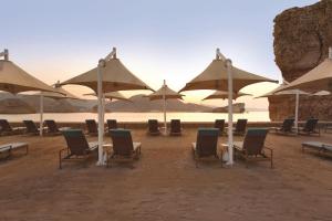 a group of chairs and umbrellas on a beach at Al Husn Hotel Muscat - managed by Hilton in Muscat