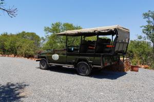 a green jeep with a canopy on a road at Umzolozolo Private Safari Lodge & Spa in Nambiti Private Game Reserve