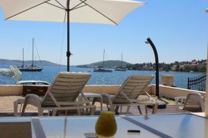 Un grupo de sillas y una sombrilla en una terraza junto al agua. en Beach Apartments Rogoznica, en Rogoznica