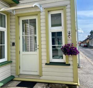 a yellow house with a white door and a flower pot at Roslep Apartment in Haapsalu +9 photos