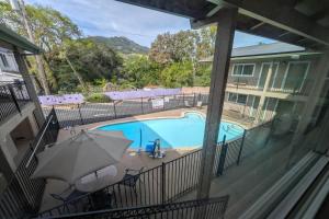 a balcony view of a swimming pool with an umbrella at Olive Tree Inn & Suites, a Howard Johnson by Wyndham in San Luis Obispo