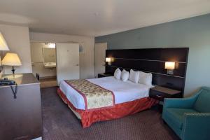a hotel room with a large bed and a chair at Olive Tree Inn & Suites, a Howard Johnson by Wyndham in San Luis Obispo +94 photos