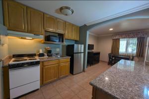 a kitchen with wooden cabinets and a white stove top oven at Olive Tree Inn & Suites, a Howard Johnson by Wyndham in San Luis Obispo