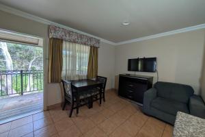 a living room with a table and a couch and a television at Olive Tree Inn & Suites, a Howard Johnson by Wyndham in San Luis Obispo