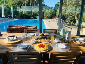 a wooden table with breakfast food on it with a pool at Villa Mandetta B&B in Santo Stefano del Sole