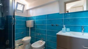 a blue tiled bathroom with a toilet and a sink at Golden Sunset - S'Archittu in S'archittu Cuglieri +29 photos