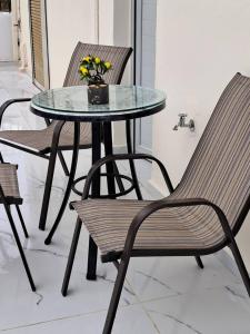 a glass table with two chairs and a table with flowers at MANI HOLIDAYS Rooms in Neo Itilo