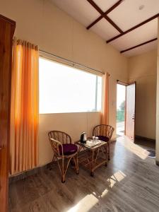 a room with a table and chairs and a large window at Mountain Vibe Resort in Chamba
