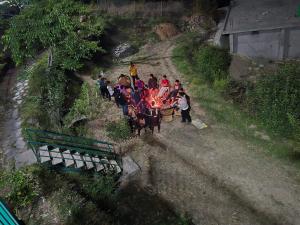 a group of people standing around a fire on a road at Mountain Vibe Resort in Chamba