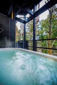 a hot tub in a building with trees in the background at Villa Qualite ヴィラカリテ in Zao