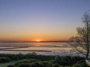 a sunset over the water with a beach at Ferienhaus Klenterdeel in Keitum +13 photos