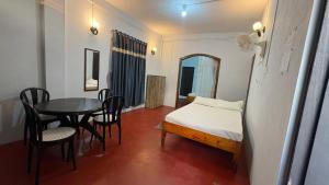 a room with a bed and a table and chairs at Riwai Root Bridge homestay in Mawlynnong +2 photos