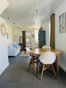 a living room with a wooden table and white chairs at Charmante maison entre Marché et Tourelles in Pornichet