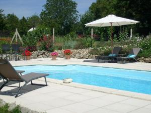 a swimming pool with two chairs and an umbrella at La Grange de Gournay in  Gournay-Loizé