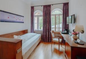 a bedroom with a bed and a desk with a computer at LA VILLA am Starnberger See in Niederpöcking +39 photos