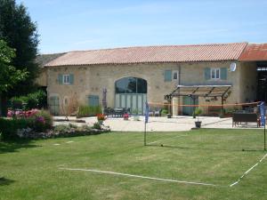 una casa con un patio con una red delante de ella en La Grange de Gournay en  Gournay-Loizé