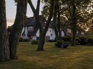 a white house with trees in front of it at Ferienhaus Klenterdeel in Keitum
