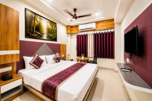 a bedroom with a bed and a flat screen tv at Hotel Apollo Sp Ring Road Odhav Ahemdabad in Ahmedabad