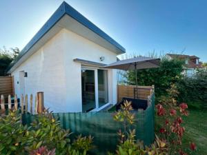a small white house with an umbrella in a yard at Le Petit Studio de Merlimont in Merlimont