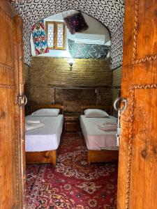 two beds in a small room with a mirror at Caravan Sarai XV century Mextar Ambar old town in Bukhara