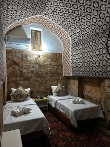 a room with two beds and a stone wall at Caravan Sarai XV century Mextar Ambar old town in Bukhara