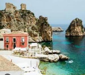 a red building in the water next to a mountain at Casa sole Sicilia in Alcamo
