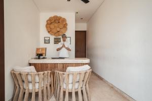 a man standing at a bar with two chairs at Eight Palms Villa Seminyak by Ini Vie Hospitality in Seminyak