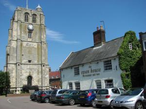 un edificio antiguo con una torre de reloj y coches aparcados delante en Swan House, en Beccles