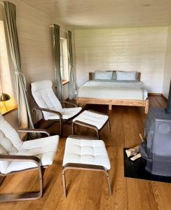 a bedroom with a bed and chairs and a stove at Lake Lodge Labanoras in Šnioriškės