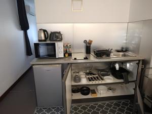 a small kitchen with a sink and a microwave at Studio à Tamaon - Malima Lodge in Pouembout