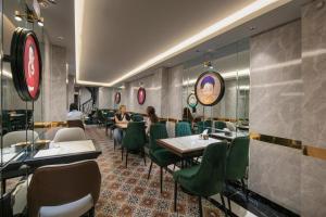 a restaurant with green chairs and tables and a clock at Hanoi Loopers Hostel & Rooftop Bar in Hanoi