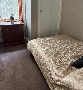 a bedroom with a bed and a dresser and a window at Preston Villa, spacious ground floor apartment in Buckie +2 photos