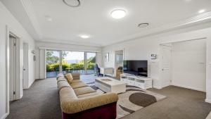 a living room with a couch and a tv at 'Gone Coastal' by HolidayCo in Killcare