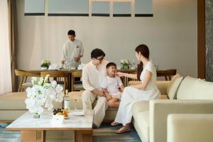 a family sitting on a couch in a living room at The Five Villas & Resort Quangnam - Danang in Hoi An +290 photos