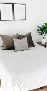 a white bed with brown pillows and a plant at Private big ROOM 20mins to Airport, 5mins to station in St Albans
