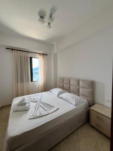 ein Schlafzimmer mit einem Bett mit weißer Bettwäsche und einem Fenster in der Unterkunft Sunset Dream Guesthouse in Himarë