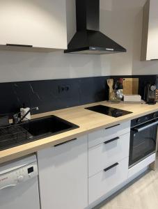 a kitchen with white cabinets and a stove top oven at Langueux Apartment in Langueux
